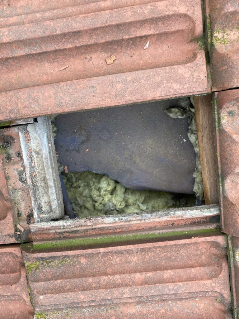 Odsłonięta wełna mineralna pod dachówką po odchyleniu membrany dachowej